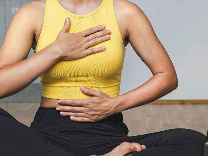 Eine Person hat eine Hand auf die Brust und die zweite auf den Bauch gelegt und atmet.