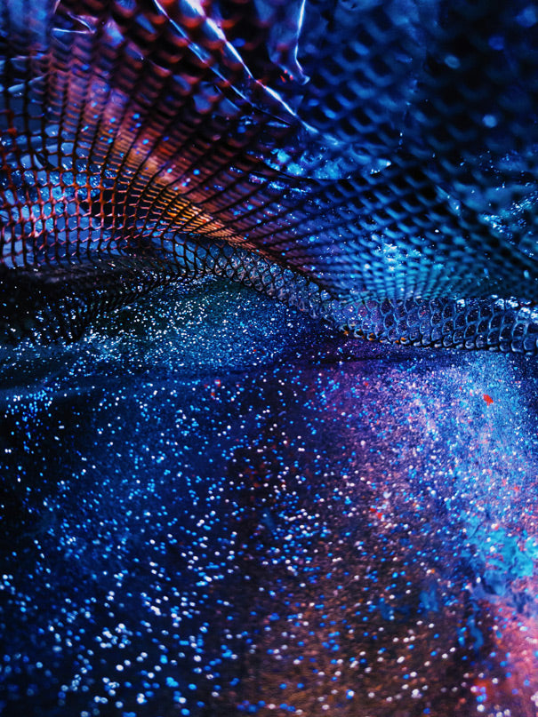 Abstrakte digitale Lichtstruktur mit schimmernden Blau-, Violett- und Magentatönen, die an fließende Datenströme und futuristische Oberflächen erinnert. Die glänzenden Reflexionen, funkelnden Partikel und dynamischen Formen vermitteln eine immersive digitale Atmosphäre voller Tiefe, Energie und moderner Technologieästhetik.